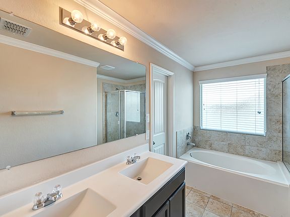 Primary Bathroom with double vanity and full-sized mirror, garden tub, shower stall, door to walk-in closet, and yes... crown molding everywhere!