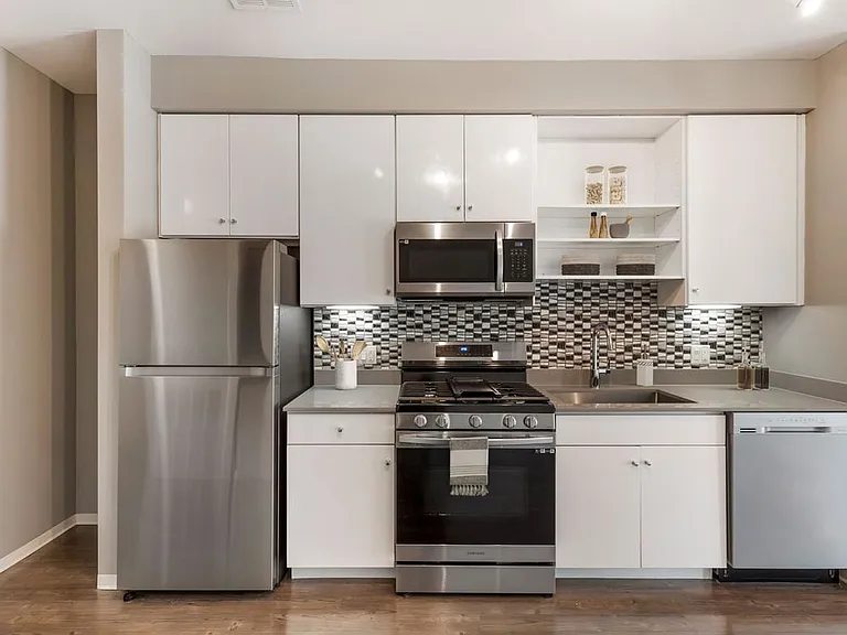 Renovated Package I kitchen with stainless steel appliances, dark quartz countertops, white cabinetry, tile backsplash, and hard surface flooring