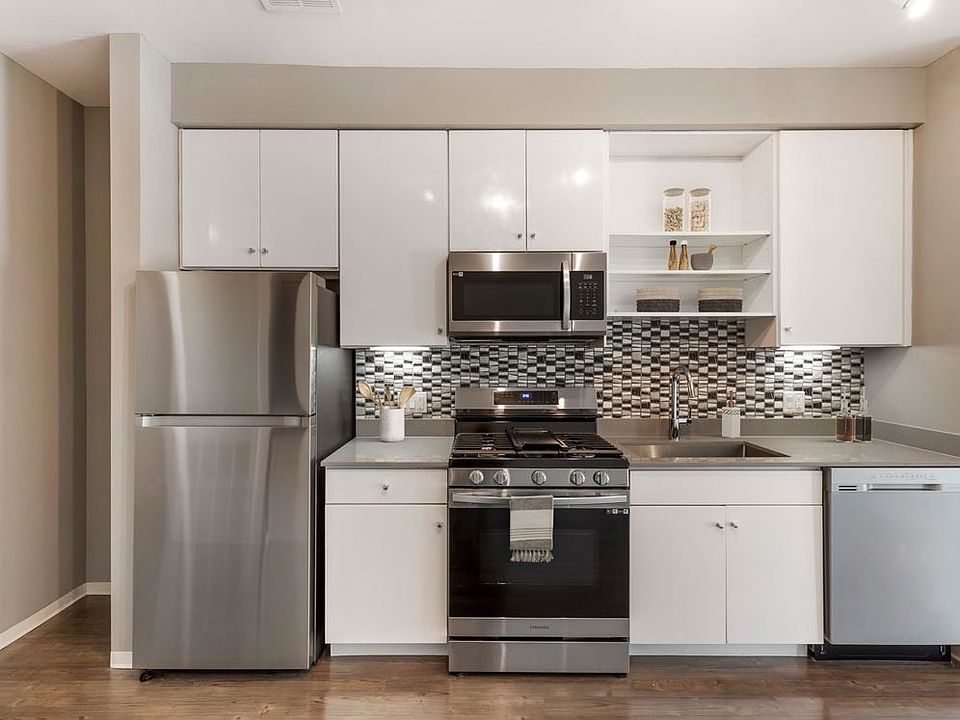 Renovated Package I kitchen with stainless steel appliances, dark quartz countertops, white cabinetry, tile backsplash, and hard surface flooring