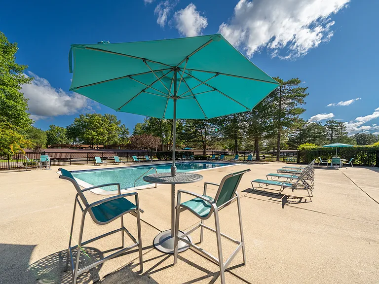Heated pool equipped with comfy lounge chairs at Westwood Village Apartments in Westland, MI