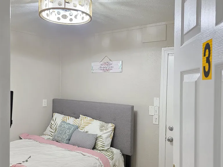 Private bedroom with a furnished bed, upholstered headboard, and overhead lighting for comfortable everyday living.