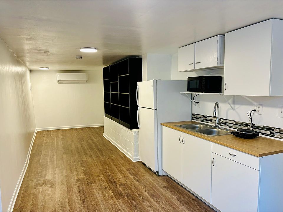 Living Room & Kitchen. Includes: refrigerator, sink, microwave and stove top burner.