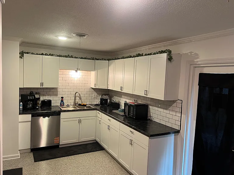 U-shaped kitchen with ample white cabinetry, subway-tile backsplash, and generous counters for meal prep and storage.