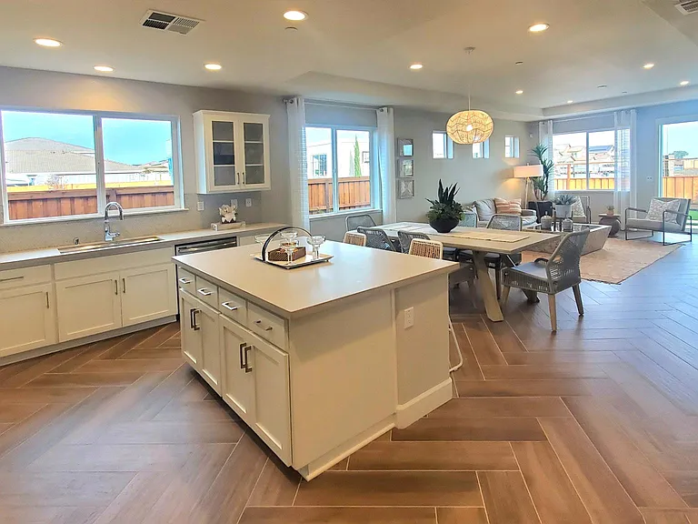 Modern island kitchen, dining room, and living room are all open in a great room
