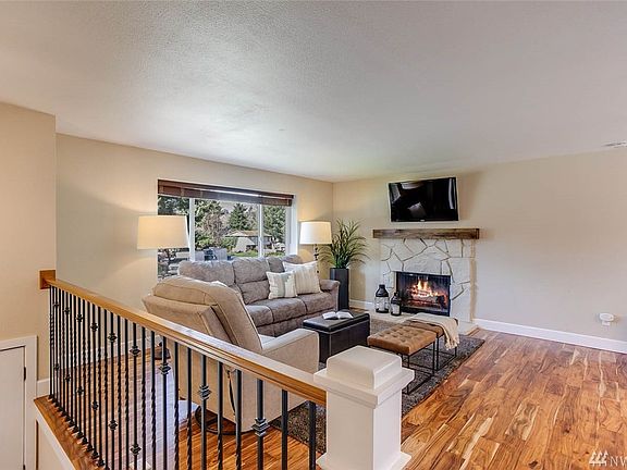 Painted stone fireplace with custom wood mantle & newly installed Acacia wood flooring enhance this appealing living room.