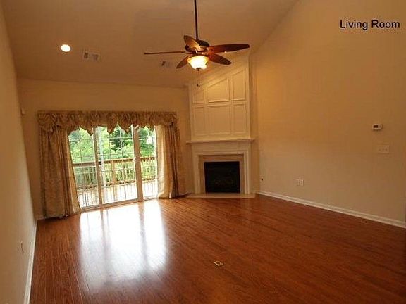 Lofted den with hardwood floors, gas fireplace, ceiling fan, and a beautiful view of the woods.