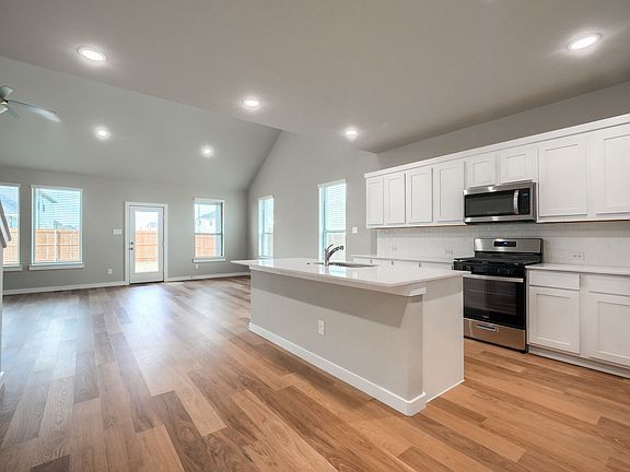 Spacious kitchen with island, Quartz countertops and modern living room with tall cathedral ceilings.