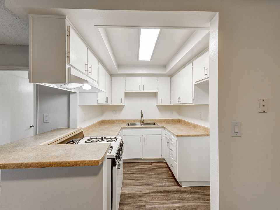 an empty kitchen with white cabinets and a counter top