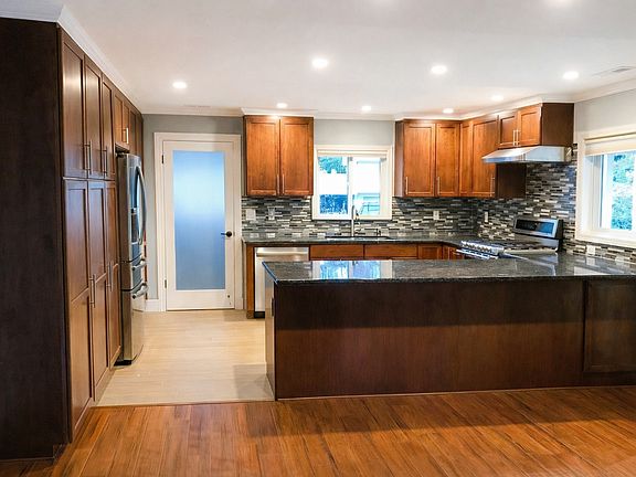 Polished stone surfaces, custom cabinetry, and a well-proportioned island offer a refined yet welcoming setting for gathering and dining.