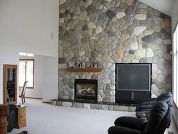 A massive gas burning fireplace surrounded by a stone wall is just incredible in the extra large liv