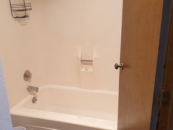 Other side of bathroom showing bathtub / shower combo and toilet.