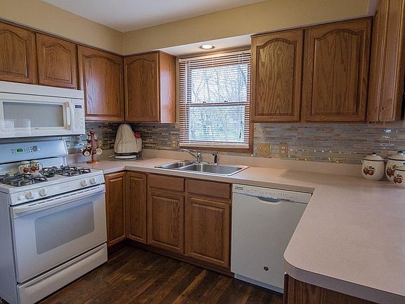 Kitchen with white appliances, new laminate flooring, tile backsplash, and loads of storage