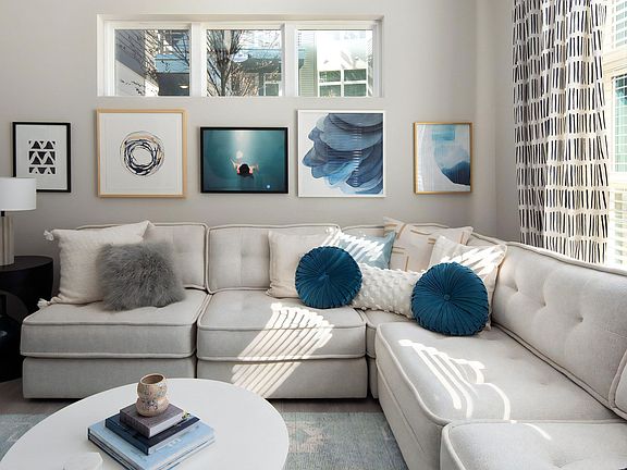 Living Room with Large Sectional Sofa, Framed Art, and Natural Light from Wide Windows