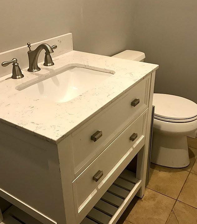 New bathroom vanity and toilet, tiled shower, stacked washer/dryer in bathroom.