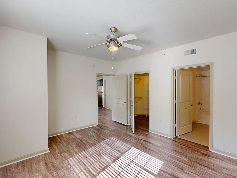 Spacious apartment bedroom with large closet, attached bathroom, and wood-style flooring.