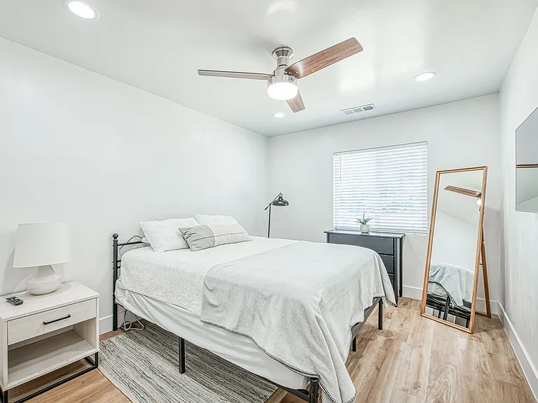 Bedroom with Cozy Bed. Ceiling Fan, Floor Mirror and Night Stand.