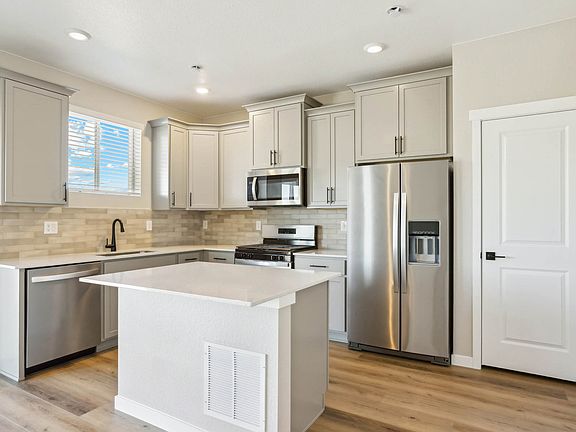 The kitchen has stainless steel appliances with plank flooring