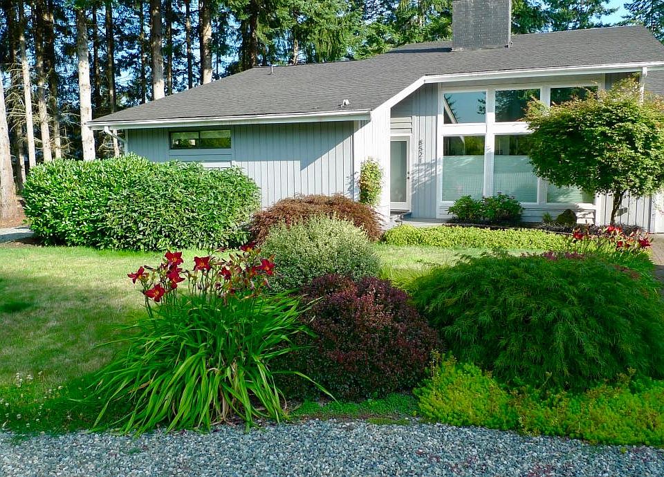 View of house entry and living room windows. Two-car garage is to the right and driveway to attached guest house is to the left.