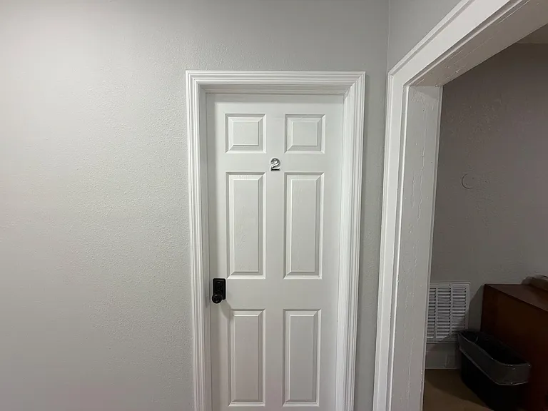 Interior hallway with a paneled door, updated trim, and neutral paint connecting to adjacent rooms.