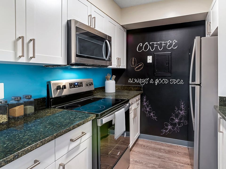 Renovated Package II kitchen with new white cabinetry, granite countertops, stainless steel appliances, painted backsplash, chalkboard accent wall, upgraded lighting and fixtures, and hard surface flooring