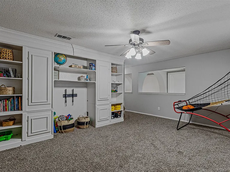 Built-in white cabinetry and shelving unit with display niches and closed storage, complemented by a ceiling fan with integrated lighting