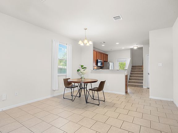 Dining space featuring stairway, a chandelier, light tile patterned floors, and recessed lighting