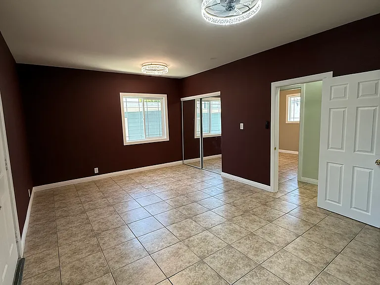 Master bedroom with two new lighting fixtures, fresh paint, new windows, new door, new sliding mirror closet doors.