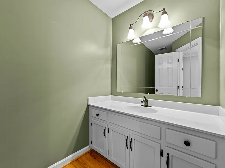 Convenient main-level powder room with white vanity, large mirror, and updated fixture.