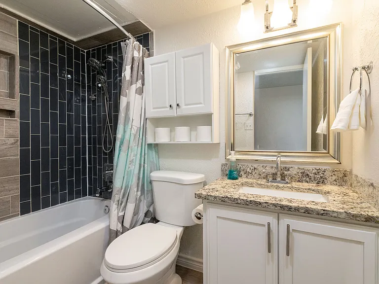 Bathroom 2 offers a convenient tub/shower combo stocked with shower gel, shampoo, and conditioner, plus a cabinet-style sink for added storage and functionality.