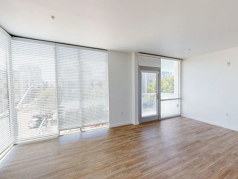 Apartment living room with wood-style flooring and floor-to-ceiling windows.