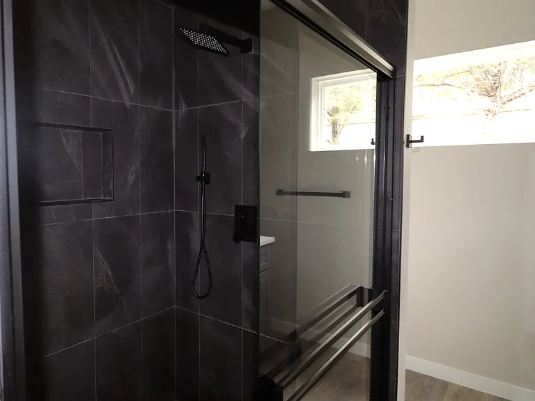 Modern walk-in shower with large-format tile, rain shower head, and built-in niche for storage. Spa-like design.