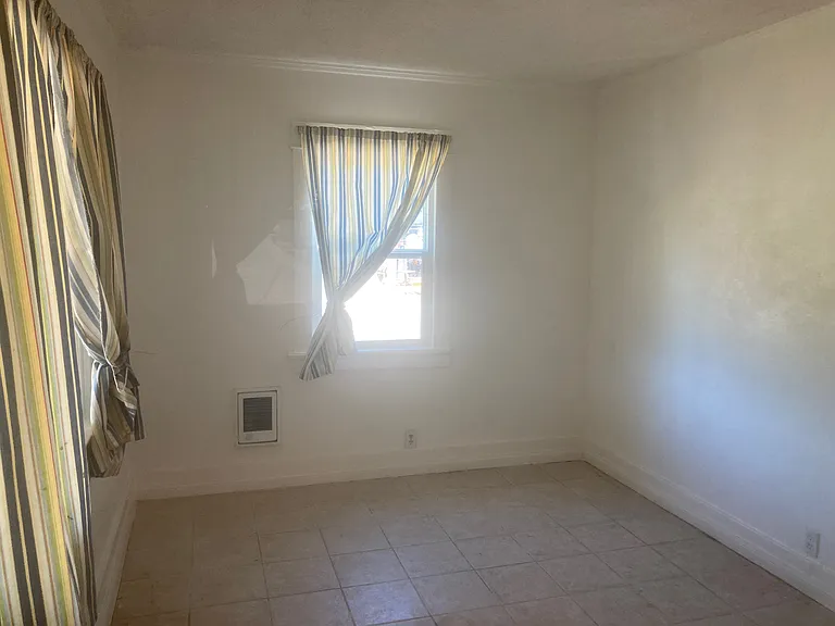 The master bedroom has a tile floor, a window to the east and two large windows to the north. This view is from the walk-in closet,