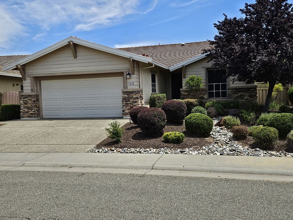 Front yard showing low water/maintenance landscaping with exposed aggregate concrete drive and walks.