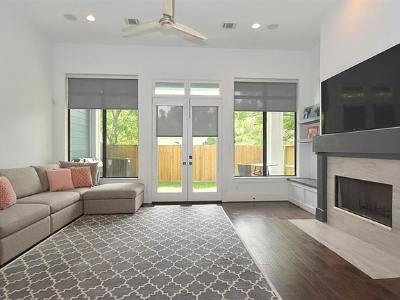 Large living area with single pane full length windows and window treatments.
