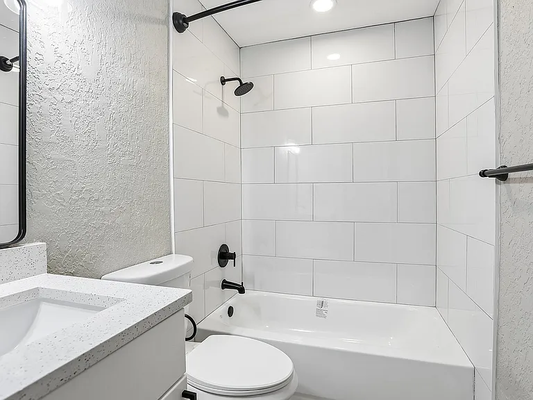 Elegant bathroom with sleek white tiles, modern black fixtures, and a pristine countertop.