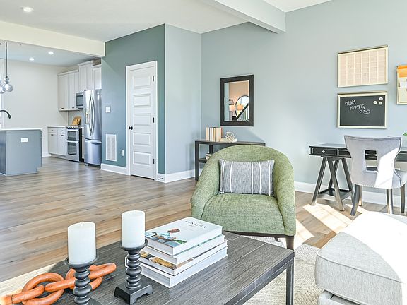 Open main floor living room and kitchen with recessed and pendant lighting in kitchen, wood floors t