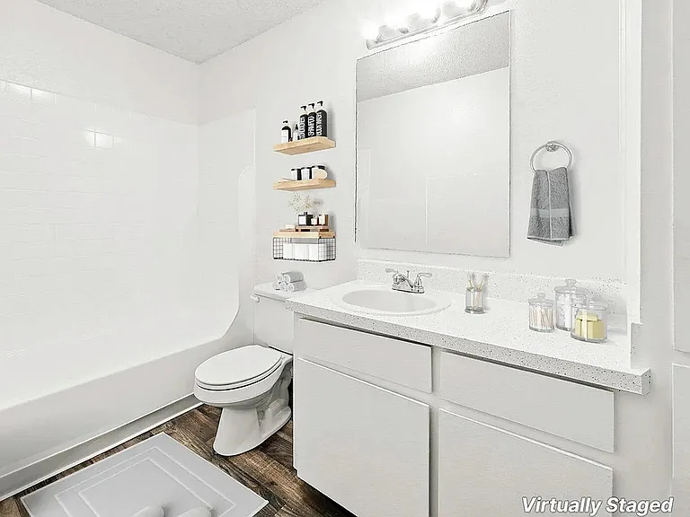 Virtually staged modern bathroom showcasing a pristine white bathtub, sleek vanity with ample counter space, and elegant shelving for toiletries. Warm wood flooring adds a touch of sophistication.