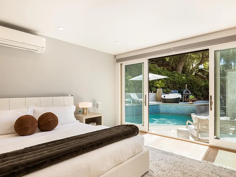 Step out from the bedroom through glass doors directly into the outdoor pool area, effortlessly merging indoor comfort with outdoor leisure.