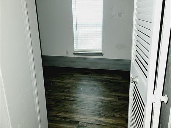 Unfurnished room with dark wood finished floors and baseboards