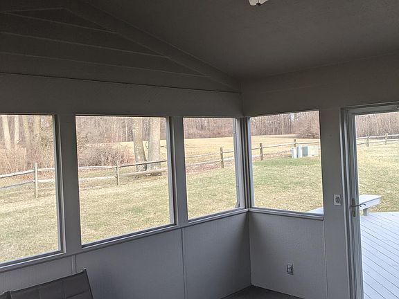 Screened-in porch with furniture and deck overlooking the park