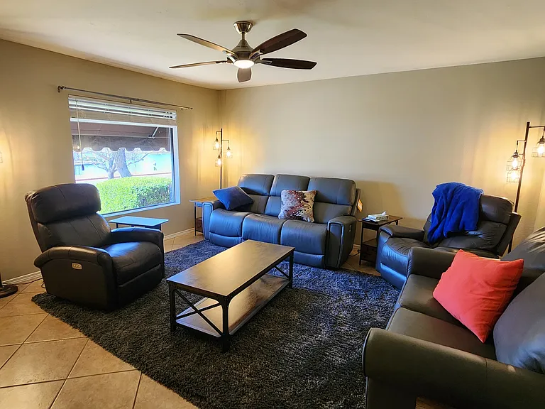 Living room with Lazy-e-boy recliners and couch. Smart Roku TV on near wall. Lake views outside window.