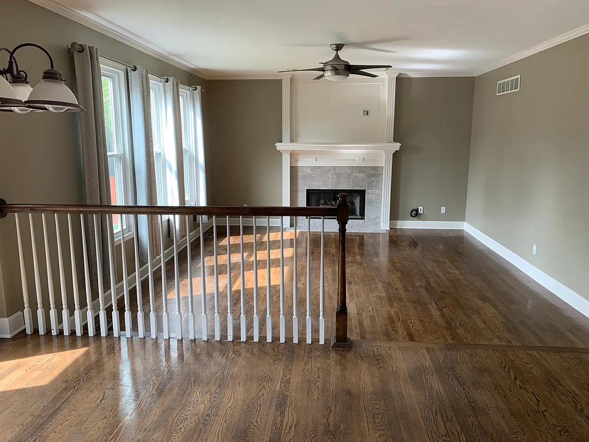 Spacious living room featuring hardwood flooring, abundant natural light, vaulted ceilings, and a cozy gas fireplace centerpiece. - 15404 Maple St