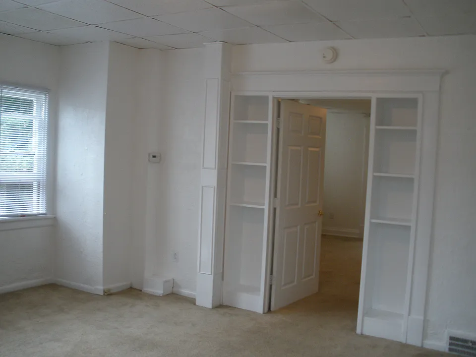 Large living room with built in curio/bookshelves on either side of 2nd bedroom door