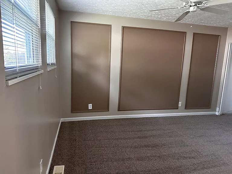 Master bedroom designer detailing, ceiling fan, two windows with mini blinds, and curtain rods.