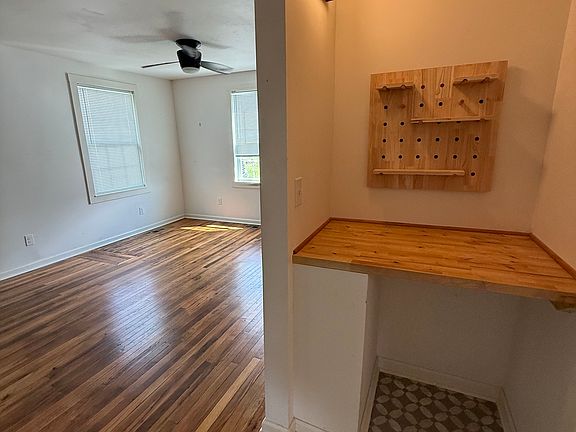 Living Room with hardwood floors. Hallway storage/display area. This photo is taken from the primary bedroom doorway.