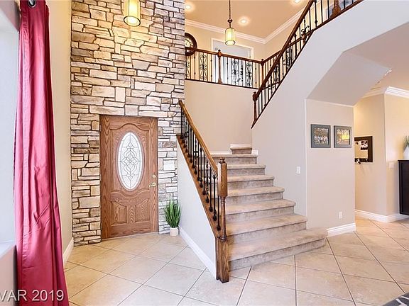 Inviting entry with vaulted ceilings, stone accent wall, open wood and iron railing.