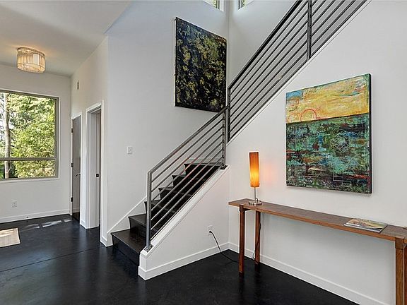 Main entry, open staircase with art alcove, industrial steel railings, heated and polished concrete floors, coat closet and powder room. 