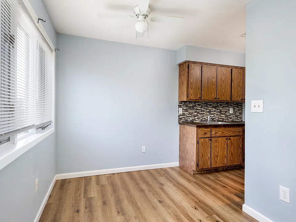 Dining area has a ceiling fan and large windows that bring in great natural light.