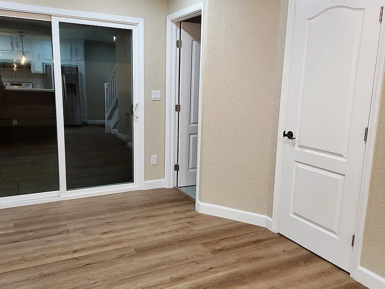 View of downstairs laundry room and 1.5 restroom, plus sliding door towards side patio.