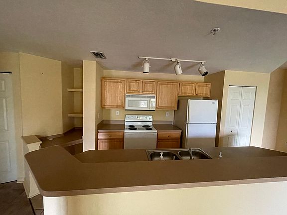 Open Kitchen looks out to living space and balcony; computer nook and shelves to the left. dishwasher next to sink.